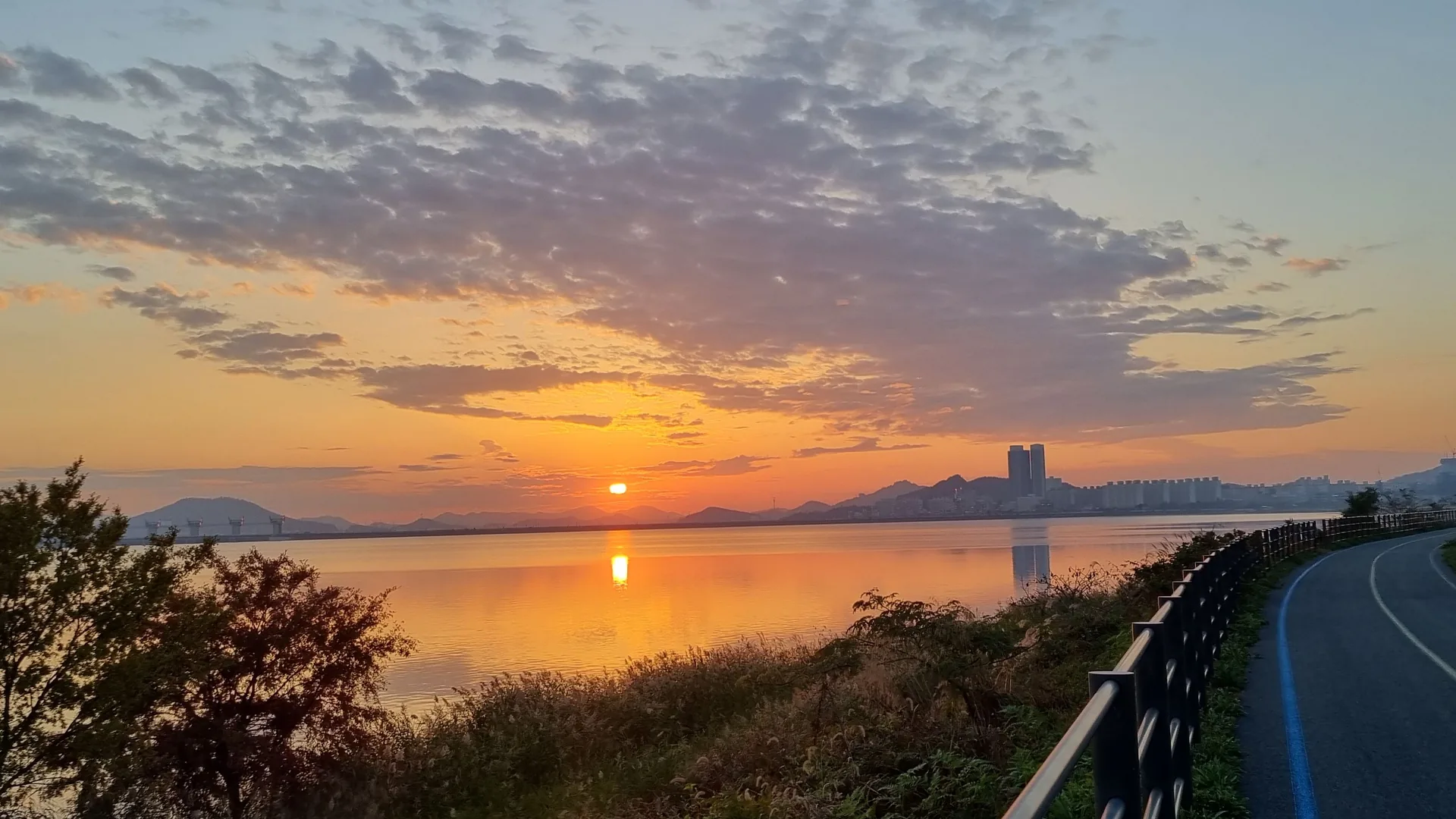 A flat riverside bike path at sunset beside the Yeongsan River