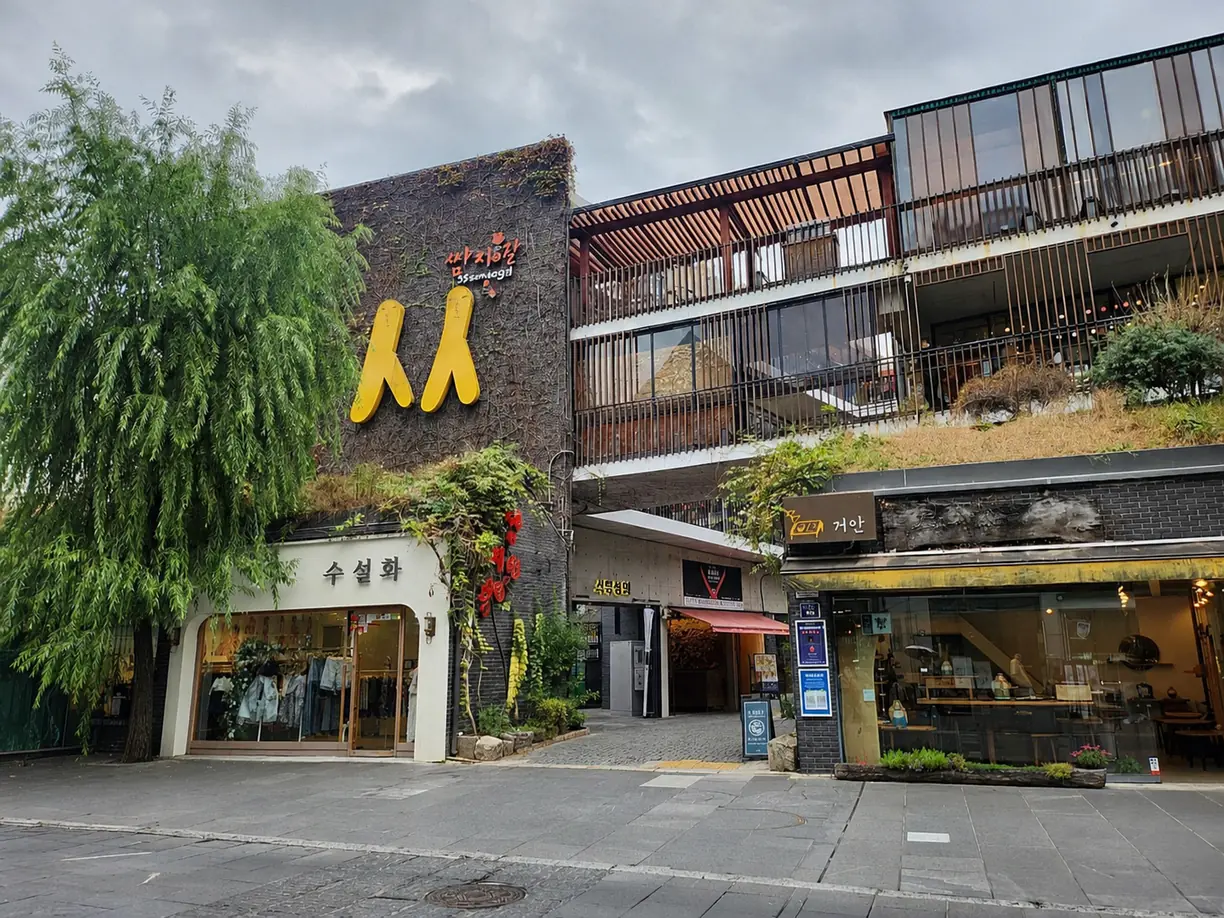 A yellow figure sculpture on a modern glass and timber building beside street-level shops